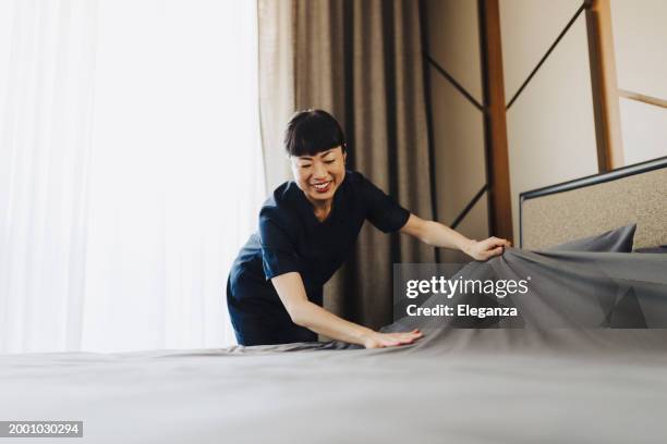 chambermaid changing bed linen on the bed in a hotel room - drap photos et images de collection