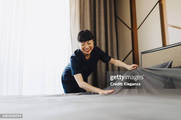 chambermaid changing bed linen on the bed in a hotel room - service occupation stock pictures, royalty-free photos & images