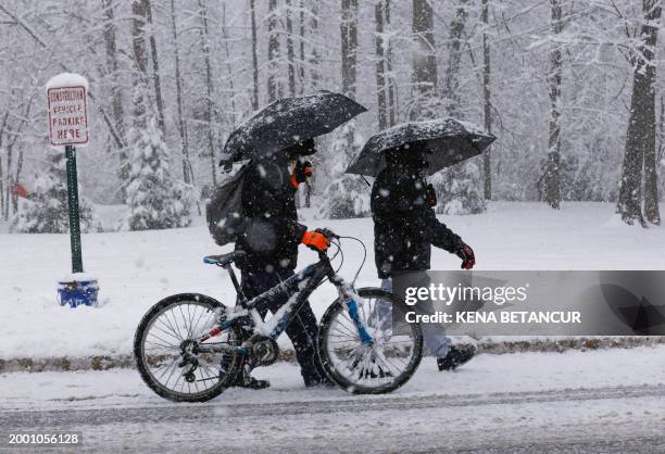 Man push a bike through the snow in Tappan, New York, on February 13, 2024. Millions of people in the northeastern US were engulfed by snow on...