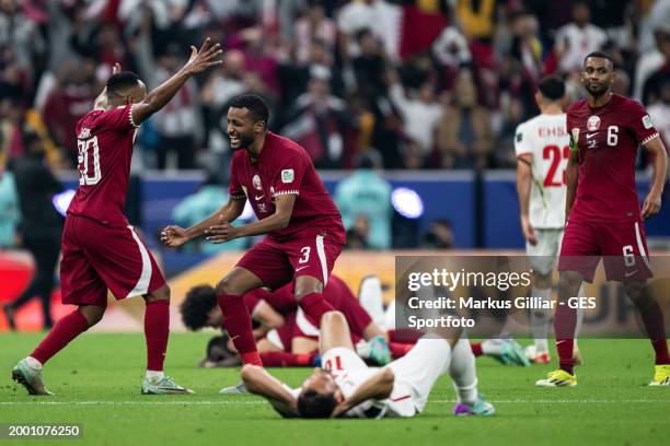 Ahmed Fathi and Almahdi Ali of Qatar celebrate victory behind the dejected Musa Al-Taamari of Jordan directly after the AFC Asian Cup final match...