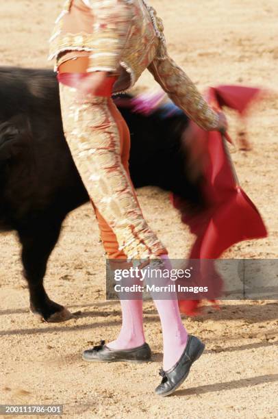 matador waving red cape in front of bull, side view (blurred motion) - corrida de touros imagens e fotografias de stock
