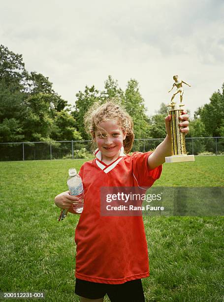 girl (6-8) holding soccer trophy on field, portrait - championship day seven stock-fotos und bilder