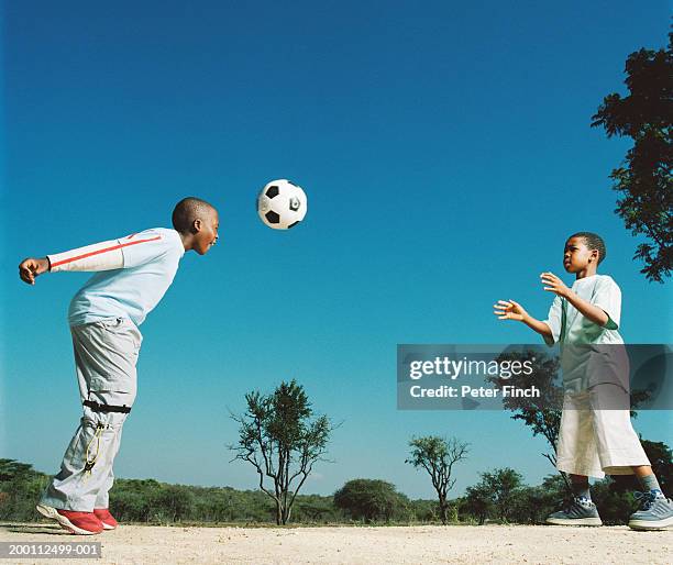 two boys (7-10), one heading football to the other - heading the ball stockfoto's en -beelden