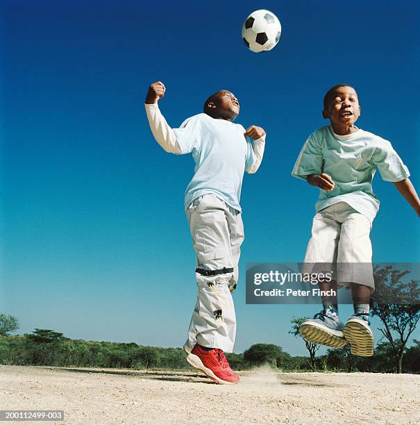 two boys (7-10) in mid-air after heading football - provincia de limpopo fotografías e imágenes de stock