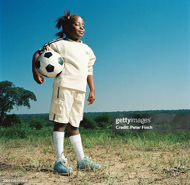 girl (7-9) holding football under arm, portrait - provincia de limpopo fotografías e imágenes de stock