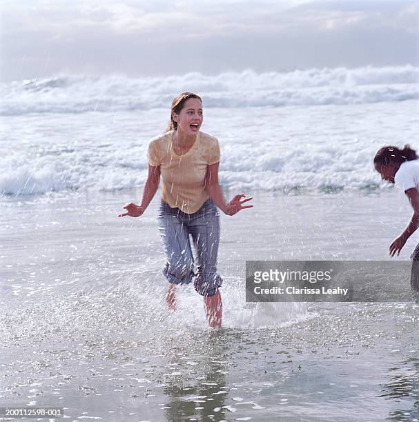 two young women playing in surf - women in wet tee shirts stock pictures, royalty-free photos & images