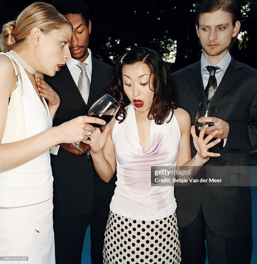 Four people holding drinks, young woman with red wine spilt down top