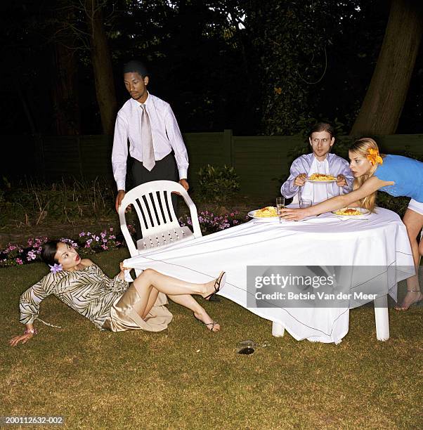 four friends dining outdoors, woman falling, pulling cloth from table - ashamed stock pictures, royalty-free photos & images