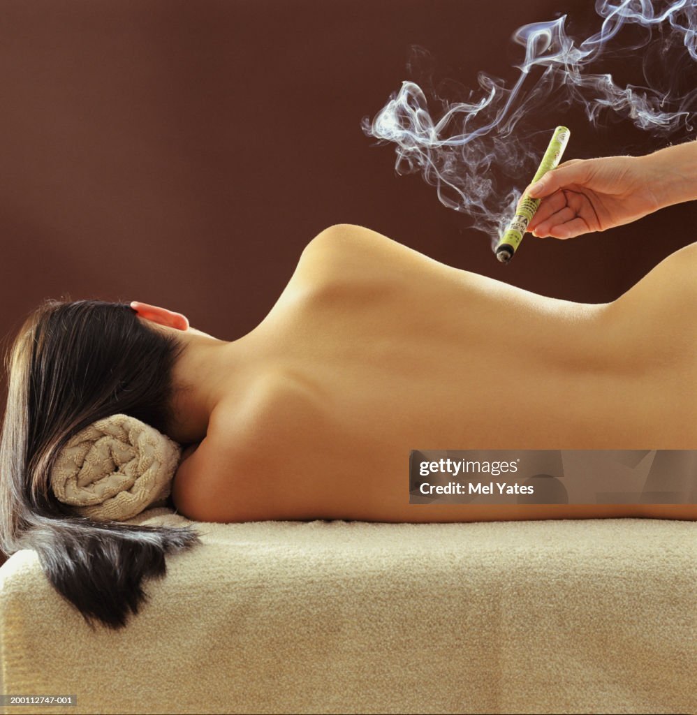 Woman lying on side, receiving cigar moxa treatment, rear view