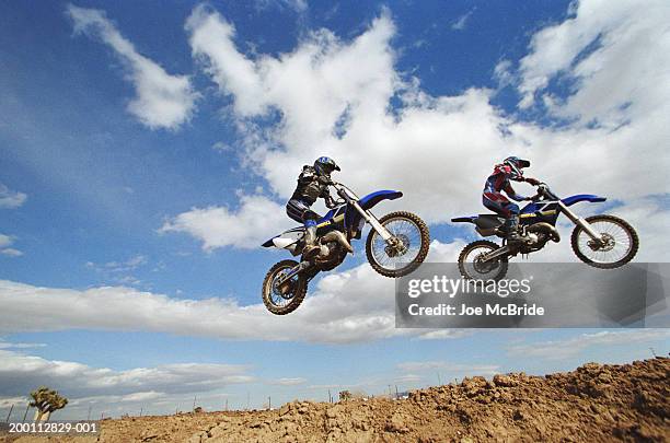 two female motocross riders in midair, side view - motocross photos et images de collection