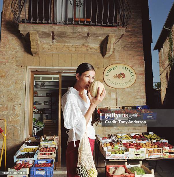 woman smelling cantaloupe at outdoor fruit stand - italian market stock pictures, royalty-free photos & images