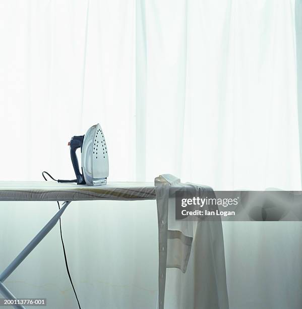 iron and shirt on ironing board - ferro da stiro foto e immagini stock