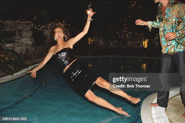 young woman, holding glass of champagne, falling into swimming pool - fall stock-fotos und bilder