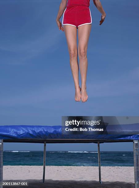 young woman jumping on trampoline, low section - trampoline jump stock-fotos und bilder