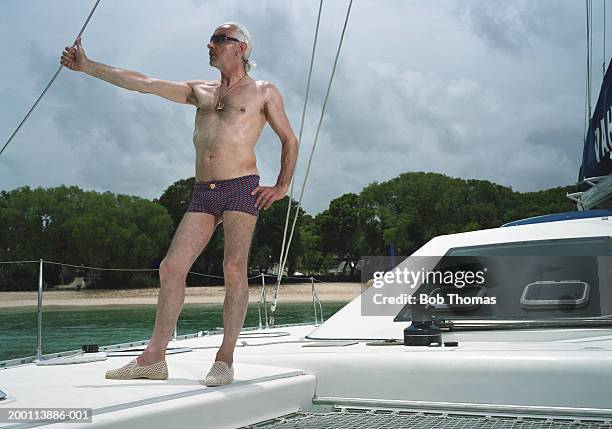mature man wearing swimming trunks, standing on boat - zu klein stock-fotos und bilder
