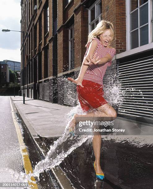 stream of water hitting young woman on pavement - puddle splashing stock pictures, royalty-free photos & images