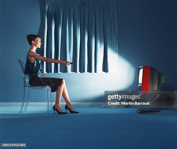 young woman pointing remote control at television, side view - avond thuis stockfoto's en -beelden