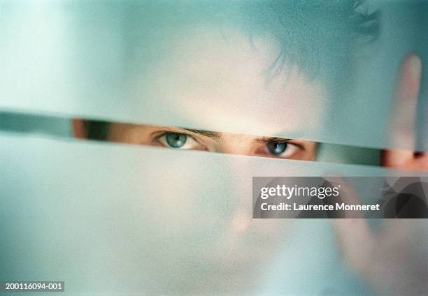 man peering through gap in frosted glass, portrait, close-up - frosted window stock pictures, royalty-free photos & images