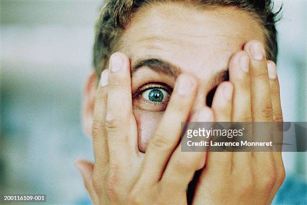 man peeping through fingers, portrait, close-up - anxiety man stock-fotos und bilder