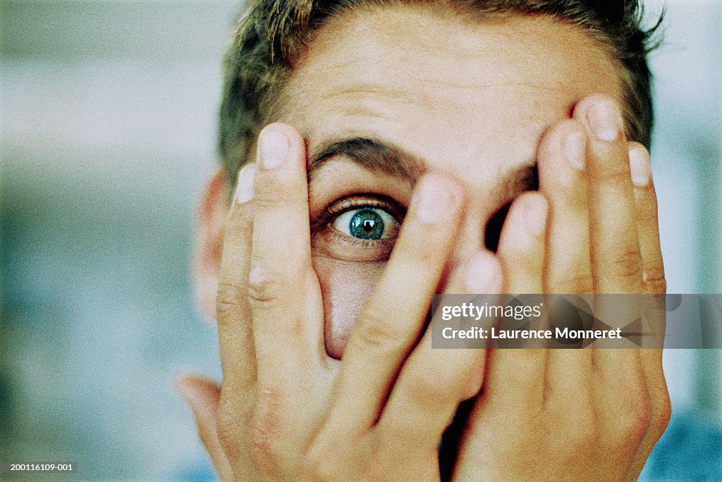 Man peeping through fingers, portrait, close-up