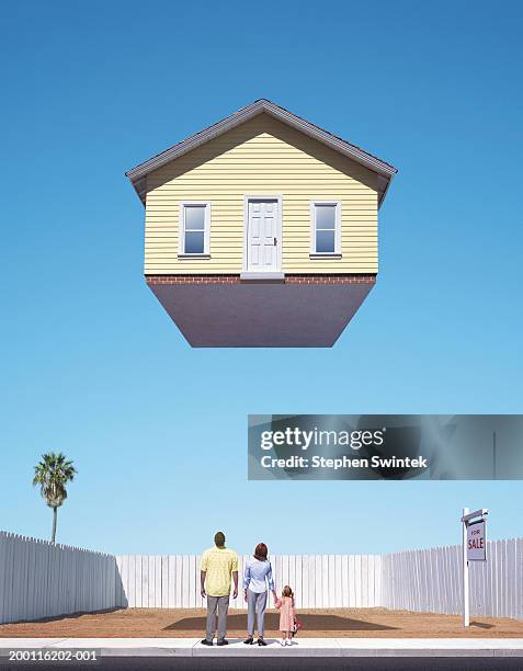 family looking up at  house floating above empty lot, rear view - flotando en el aire fotografías e imágenes de stock