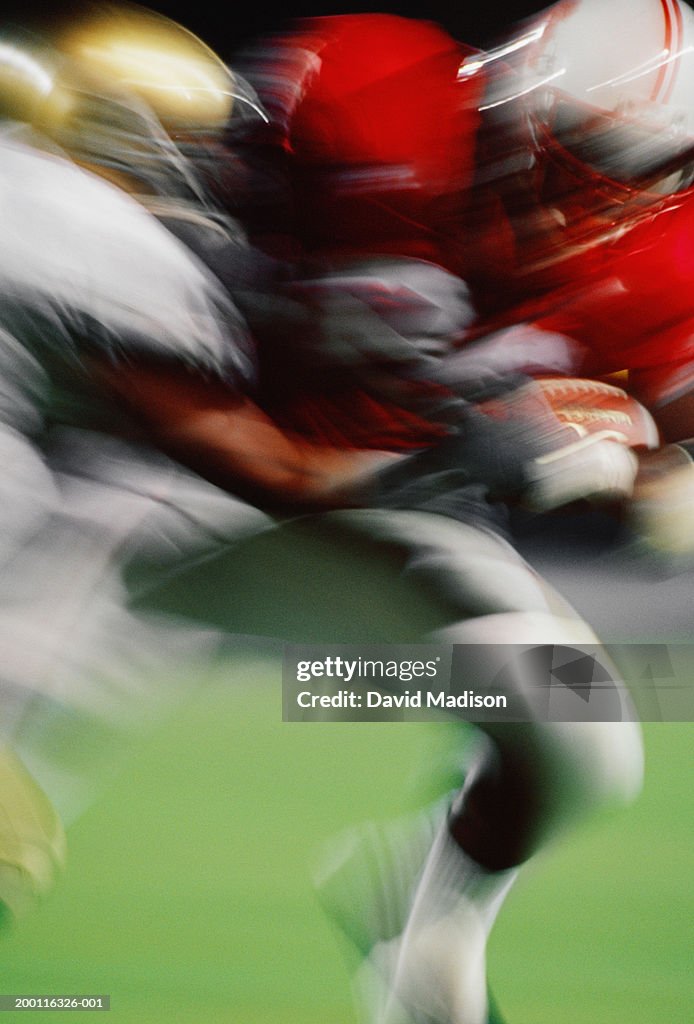 Football player tackling running back, close-up (blurred motion)