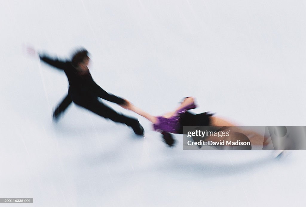 Couple figure skating on ice, elevated view (blurred motion)