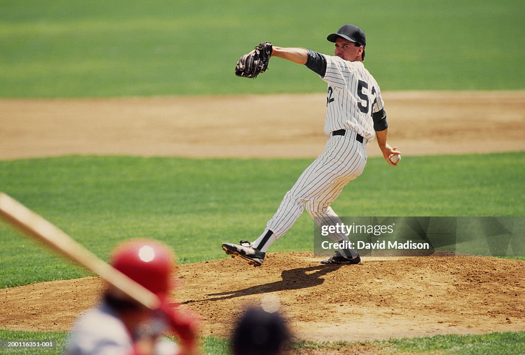 Baseball pitcher preparing to pitch ball to batter