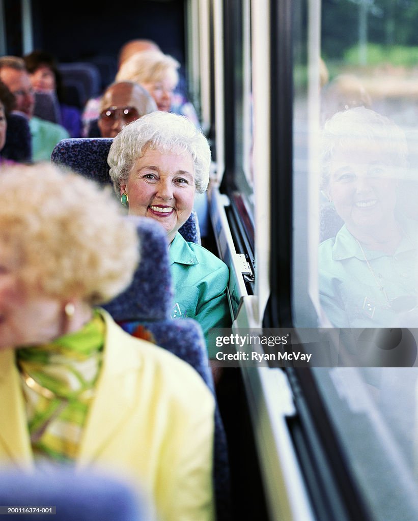 Elderly woman on coach bus, smiling, portrait