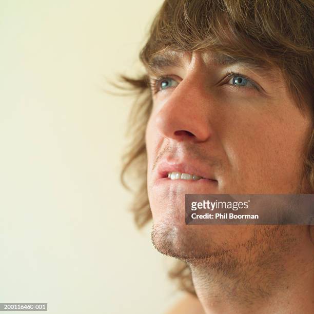 young man biting lip, close-up - op de lip bijten stockfoto's en -beelden