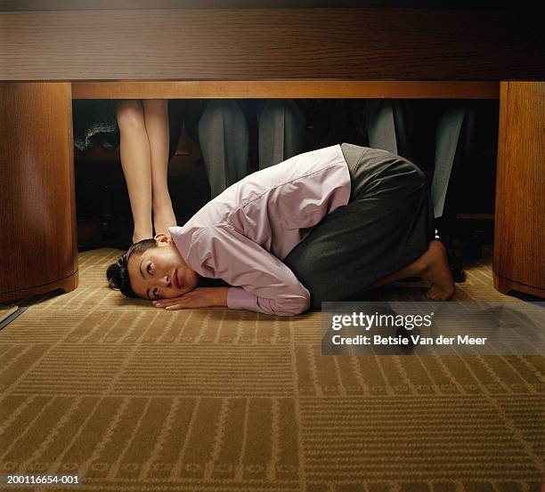 young woman curled up under table at colleagues' feet - love photos et images de collection