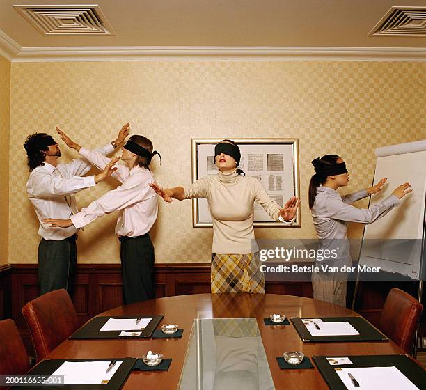 group of blindfolded executives in conference room, arms outstretched - blinddoek stockfoto's en -beelden