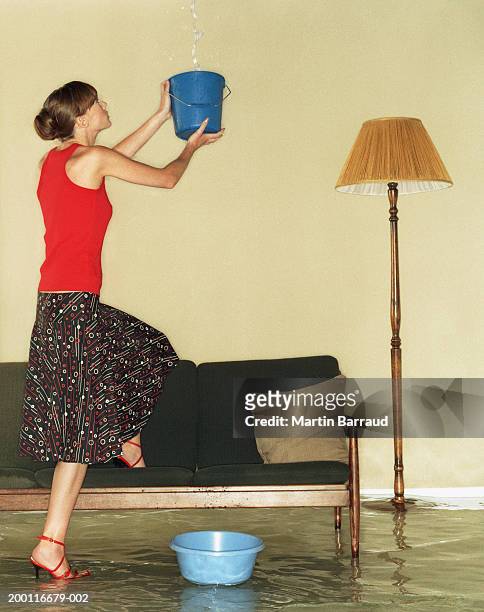 young woman catching water in bucket in flooded room - lampshade skirt stock pictures, royalty-free photos & images
