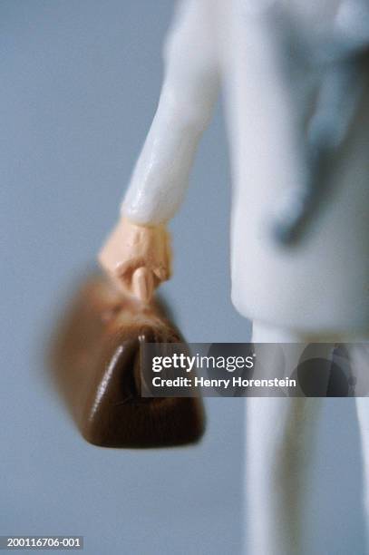 doctor figurine carrying medical bag, focus on hand - arzt koffer stock-fotos und bilder