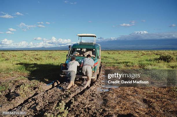 two men pushing vehicle out of mud, rear view - pushing stock pictures, royalty-free photos & images