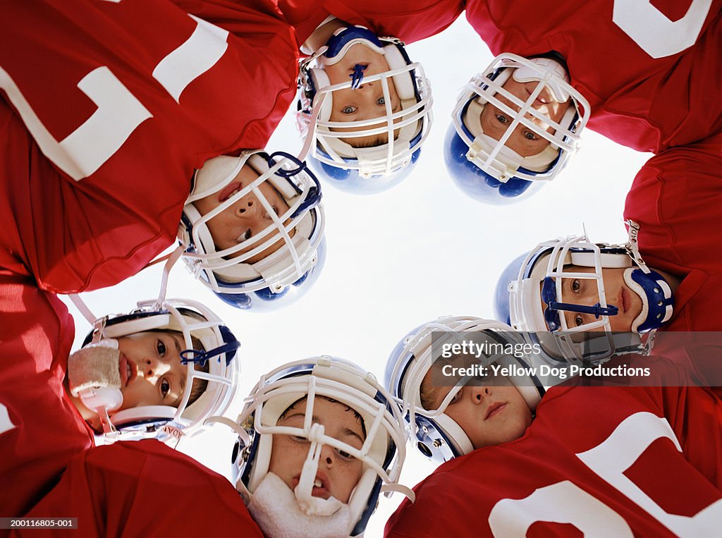 Pee wee football team (10-12) in huddle, portrait, low angle view