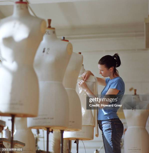 young woman pinning fabric to dressmakers dummy, side view - dressmakers model stock pictures, royalty-free photos & images