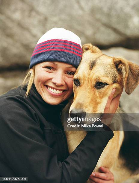 woman wearing knit cap, hugging dog, portrait - dog and owner stockfoto's en -beelden