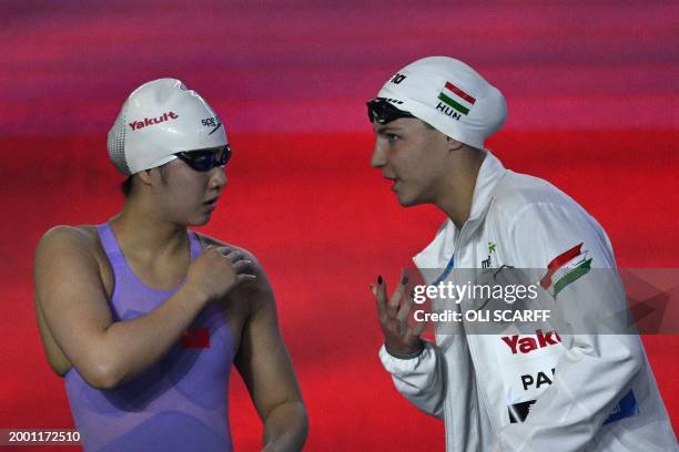 Hungary's Nikolett Padar speask with China's Yanhan Ai before a semi-final of the women's 200m freestyle swimming event during the 2024 World...