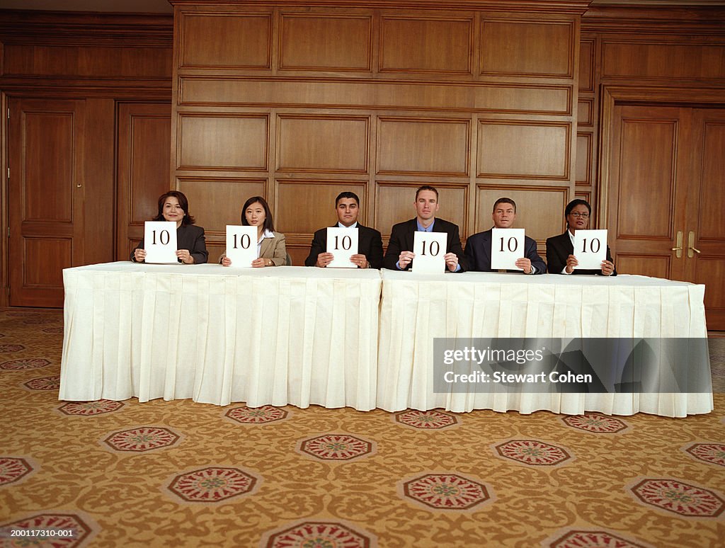 Business professionals sitting at table, holding score cards