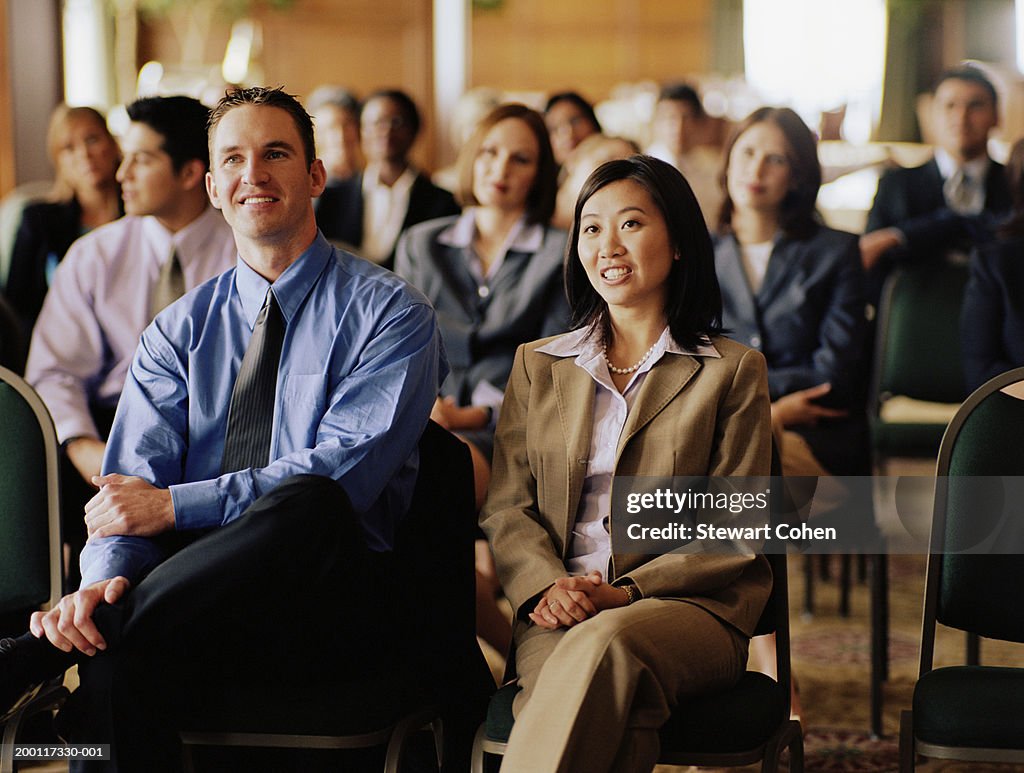 Business professionals sitting in audience at conference