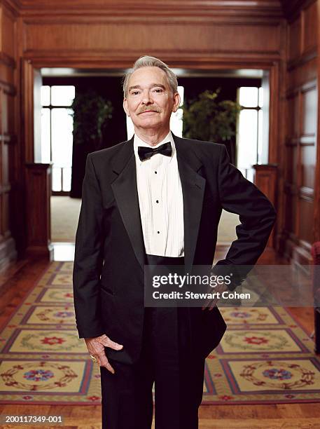 senior man wearing tuxedo, standing in hallway, portrait - smoking activity stock-fotos und bilder