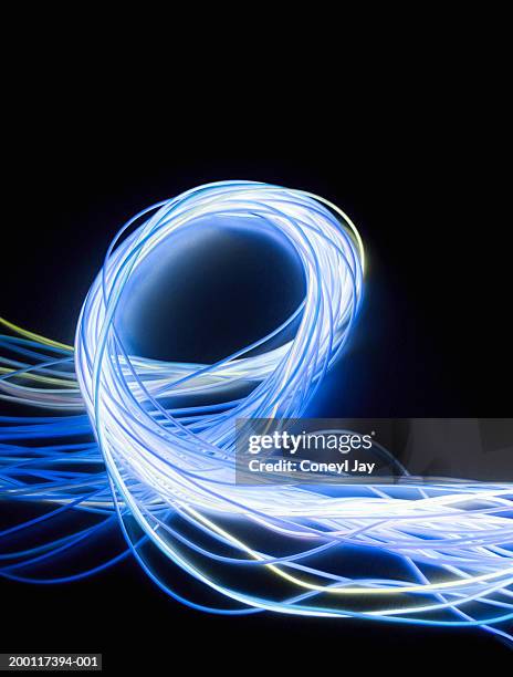 looped bundle of fibre optic wires against black background, close-up - fiber optics stock-fotos und bilder