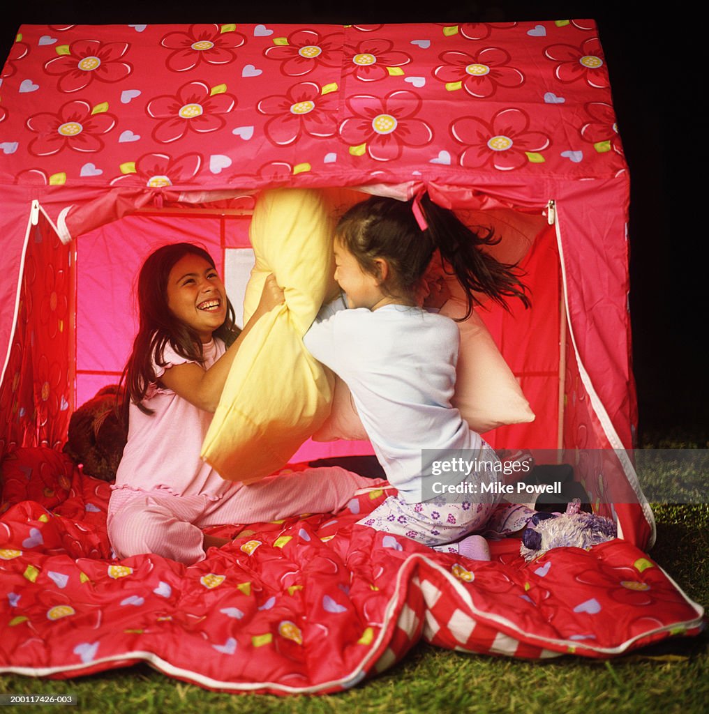 Girls (5-10) camping in back yard, having pillow fight in tent