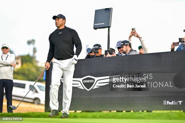 Tiger Woods prepares to play a tee shot as members of the media take photos and video during practice for The Genesis Invitational at Riviera Country...