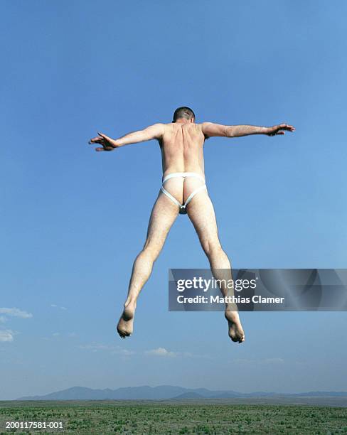 man wearing athletic support, jumping in mid air, rear view - jockstrap stock pictures, royalty-free photos & images