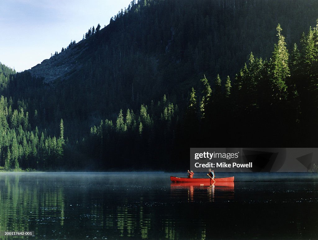 Father and son (7-9) canoeing on lake