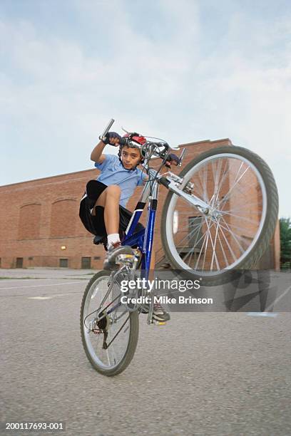 boy (10-12) doing a wheelie, portrait - wheelie imagens e fotografias de stock