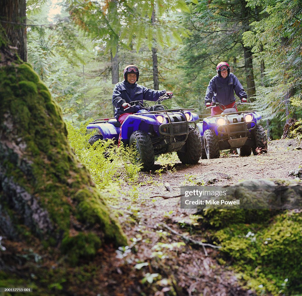 Couple riding ATV's through forest, portrait