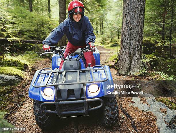 woman driving atv through forest - offroad stock-fotos und bilder
